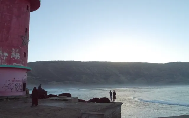 La baie d'Imsouane au lever du soleil — surfeurs alignés sur le long mur droit de la Cathédrale, l'une des plus longues vagues d'Afrique du Nord