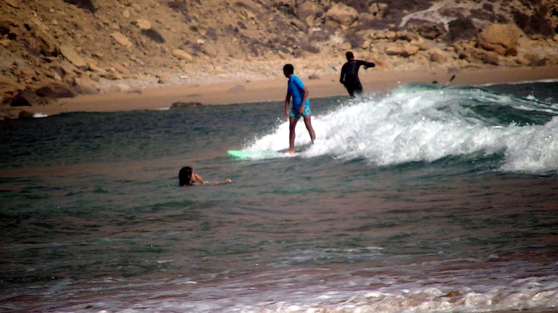 Surfeur sur une vague droite à Imsouane — deuxième surfeur ramant en arrière-plan, fond rocheux typique du spot
