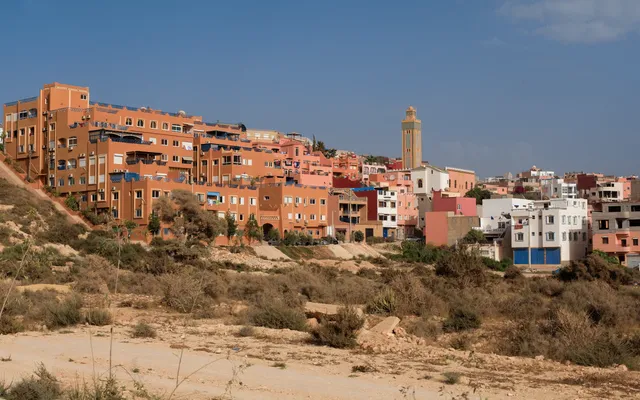 Tamraght — maisons colorées étagées sur la colline au-dessus de l'Atlantique, mosquée du village au centre